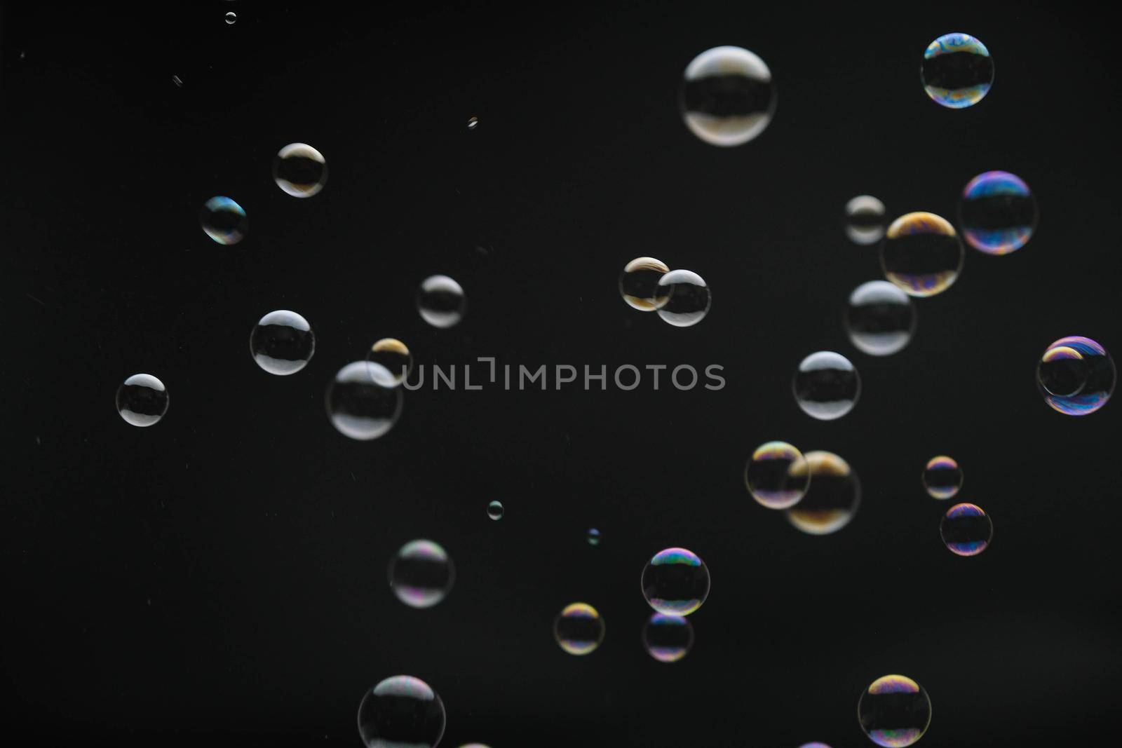 Flying soap bubbles on black background. Abstract soap bubbles with colorful reflections. Soap bubbles in motion background. by TEERASAK