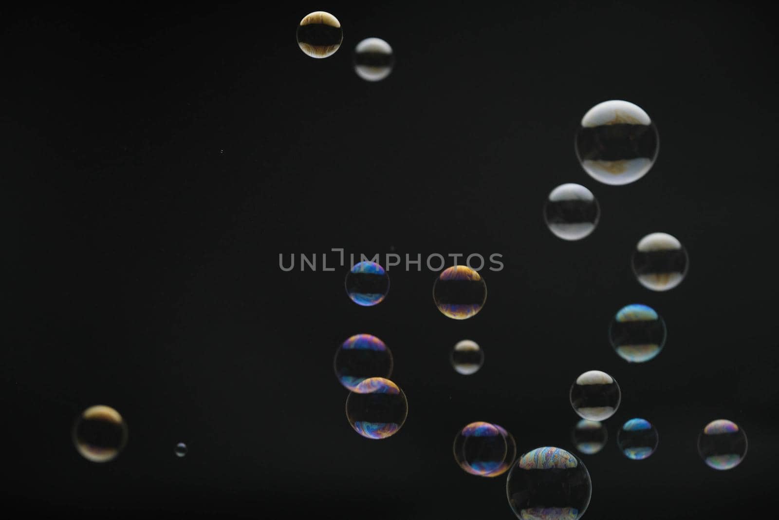 Flying soap bubbles on black background. Abstract soap bubbles with colorful reflections. Soap bubbles in motion background.
