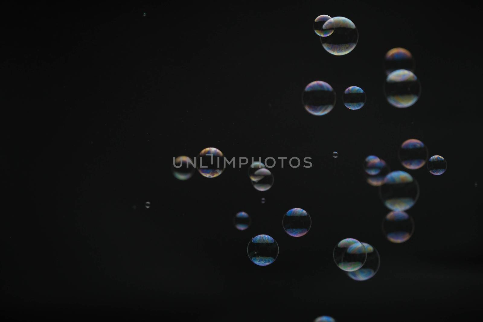 Flying soap bubbles on black background. Abstract soap bubbles with colorful reflections. Soap bubbles in motion background.