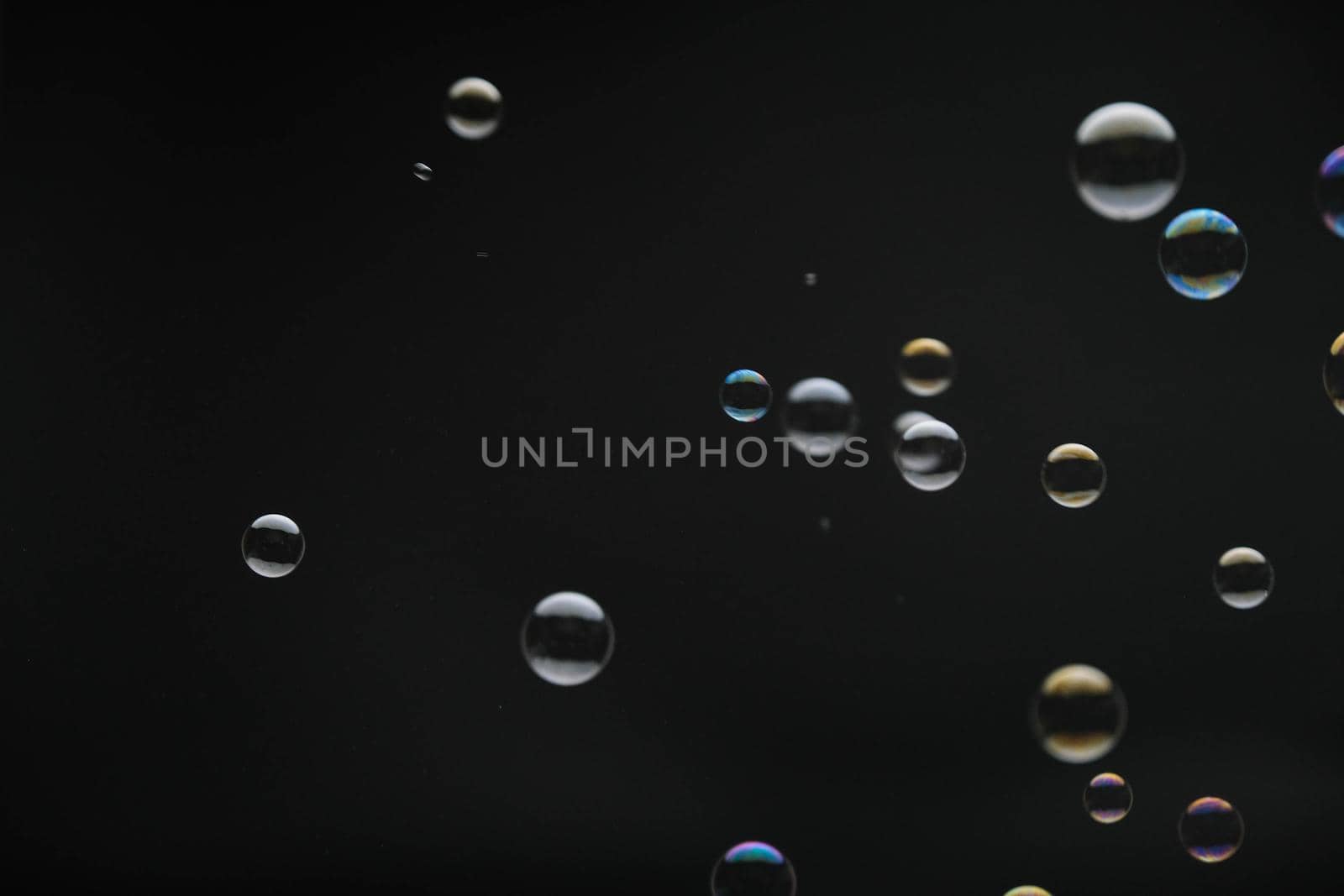 Flying soap bubbles on black background. Abstract soap bubbles with colorful reflections. Soap bubbles in motion background.