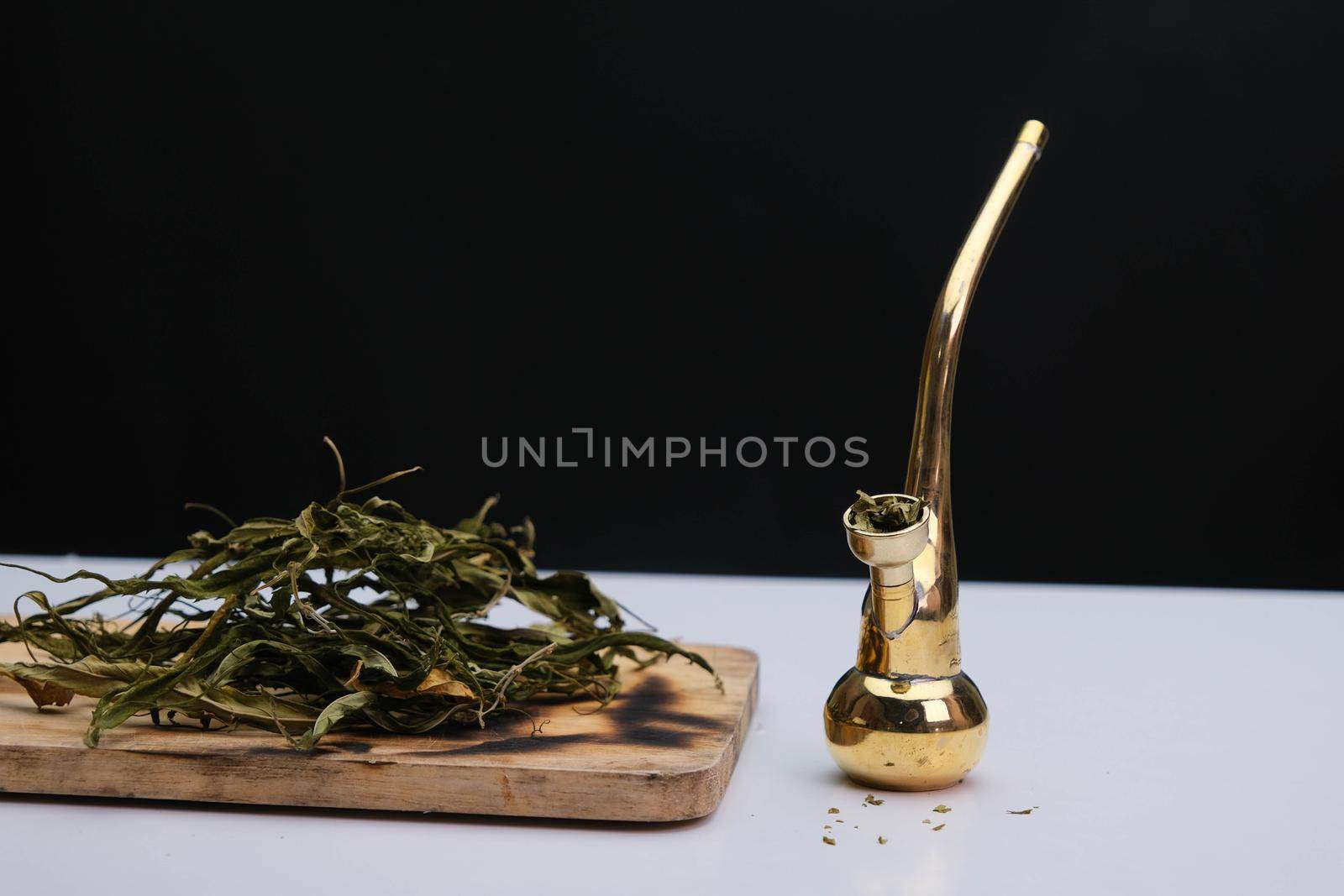 Close-up of cannabis leaves on a wooden board and smoke coming out of a pipe on a black background. Cannabis legalisation.