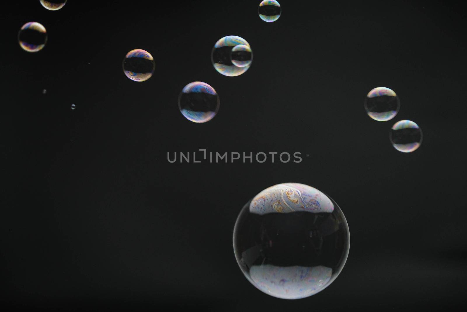 Flying soap bubbles on black background. Abstract soap bubbles with colorful reflections. Soap bubbles in motion background.