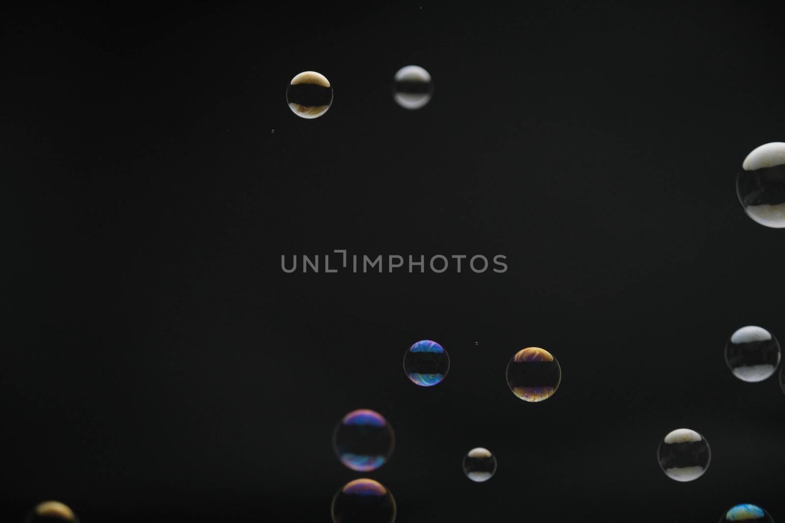 Flying soap bubbles on black background. Abstract soap bubbles with colorful reflections. Soap bubbles in motion background.