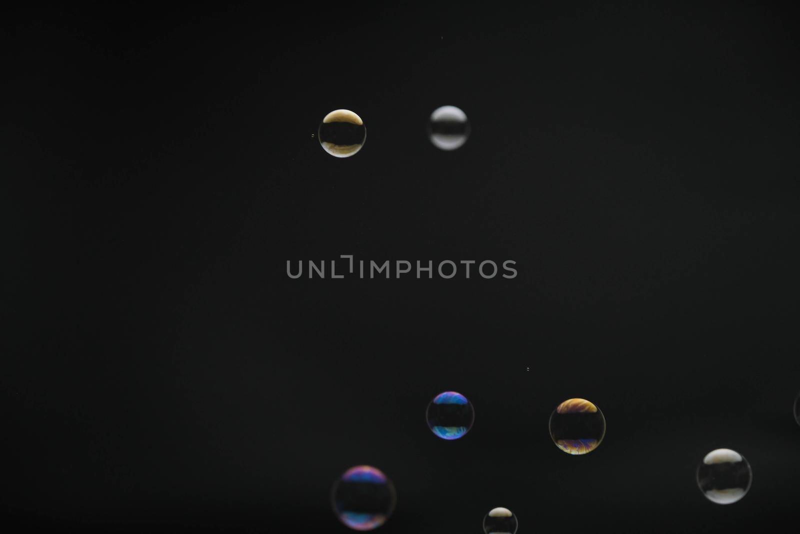 Flying soap bubbles on black background. Abstract soap bubbles with colorful reflections. Soap bubbles in motion background.