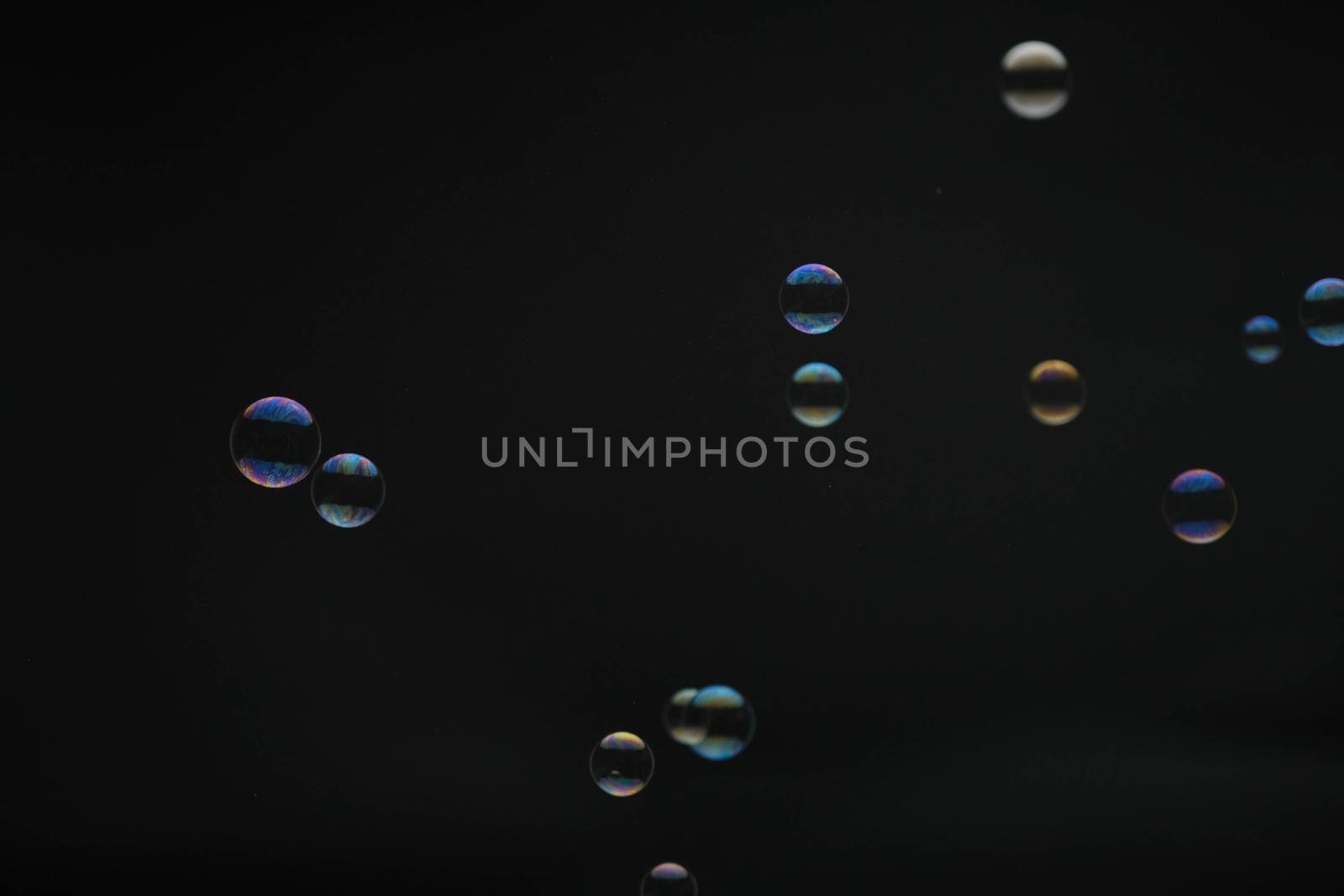 Flying soap bubbles on black background. Abstract soap bubbles with colorful reflections. Soap bubbles in motion background.