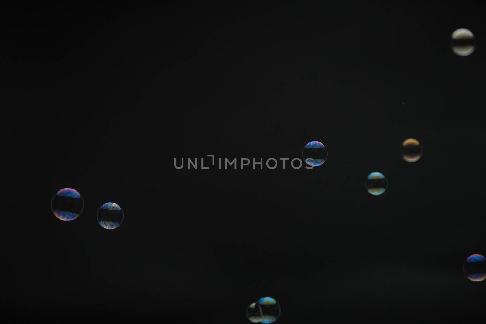 Flying soap bubbles on black background. Abstract soap bubbles with colorful reflections. Soap bubbles in motion background.