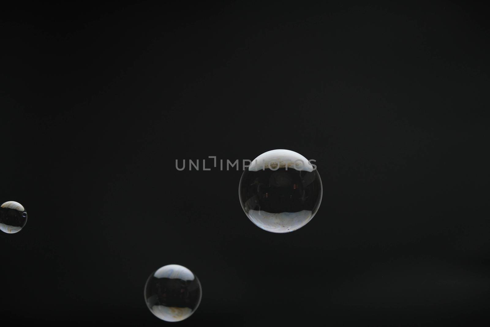 Flying soap bubbles on black background. Abstract soap bubbles with colorful reflections. Soap bubbles in motion background.