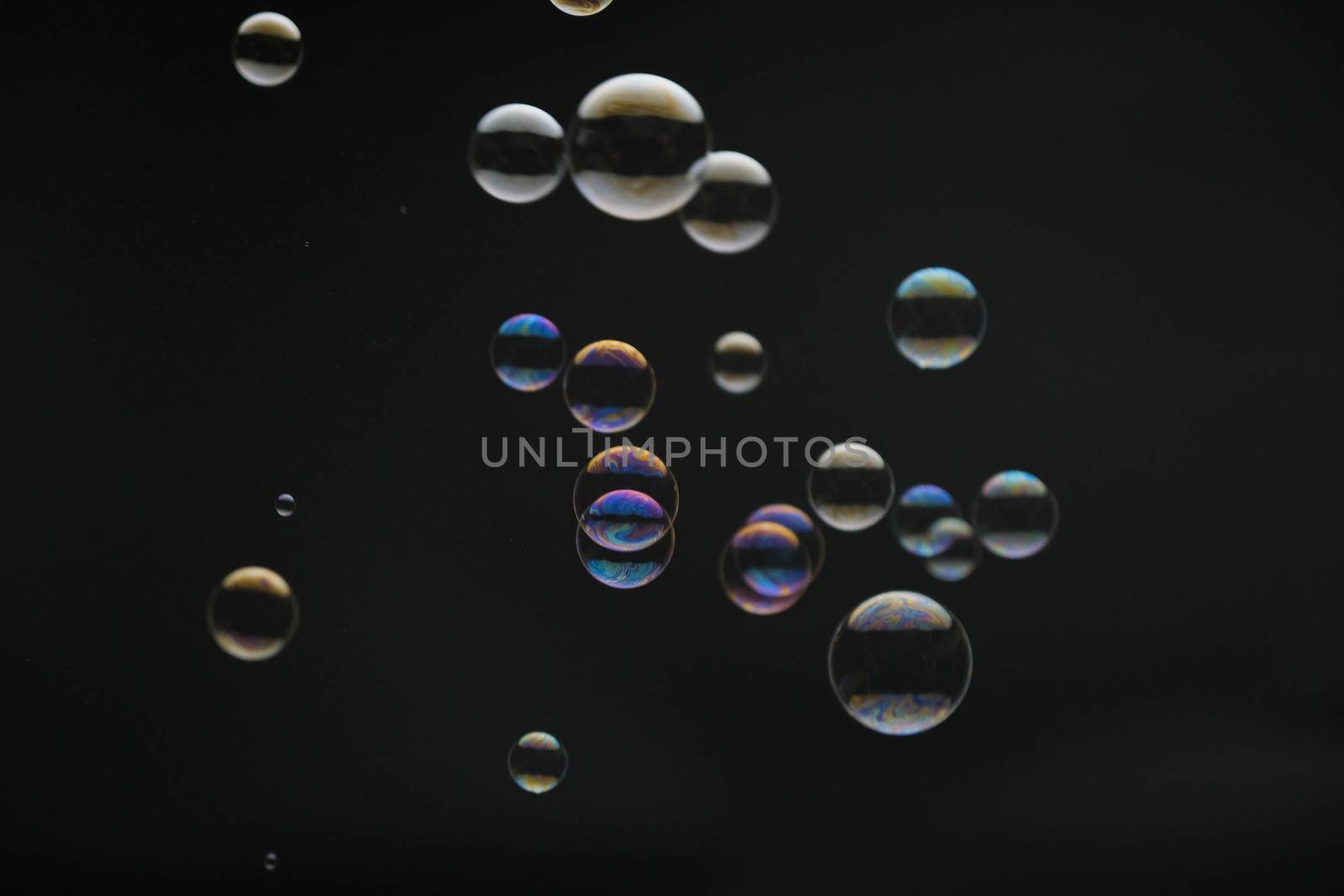 Flying soap bubbles on black background. Abstract soap bubbles with colorful reflections. Soap bubbles in motion background. by TEERASAK