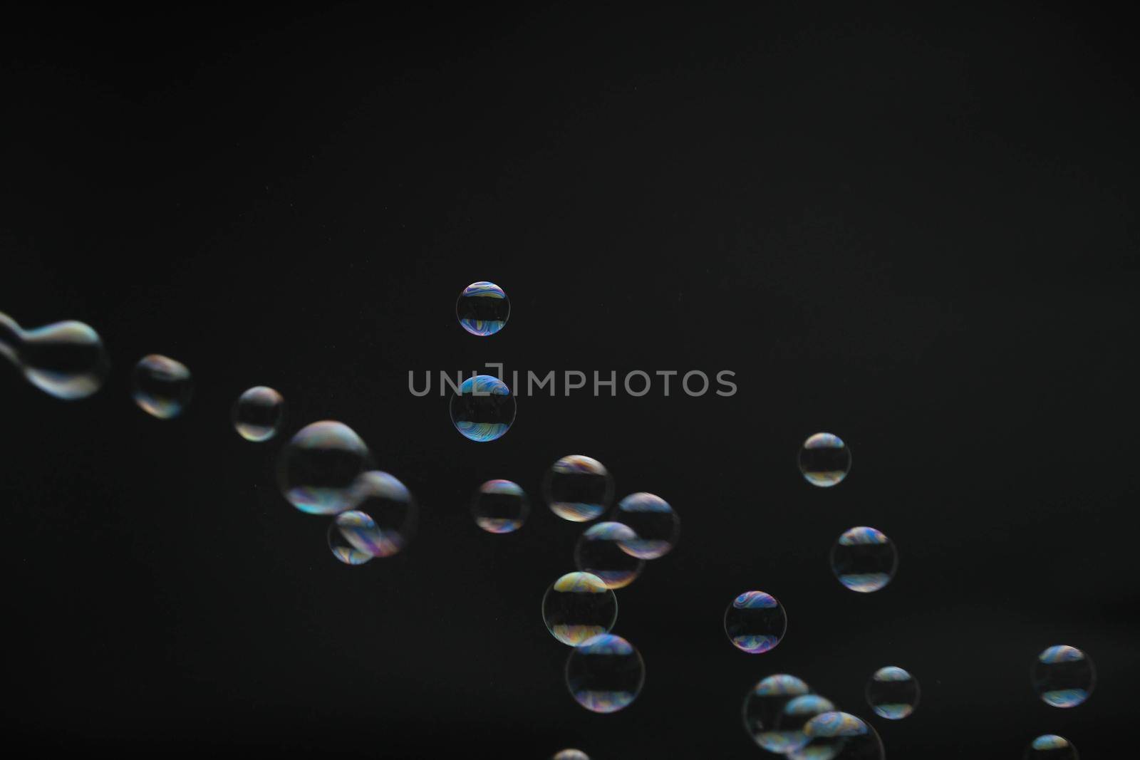 Flying soap bubbles on black background. Abstract soap bubbles with colorful reflections. Soap bubbles in motion background. by TEERASAK