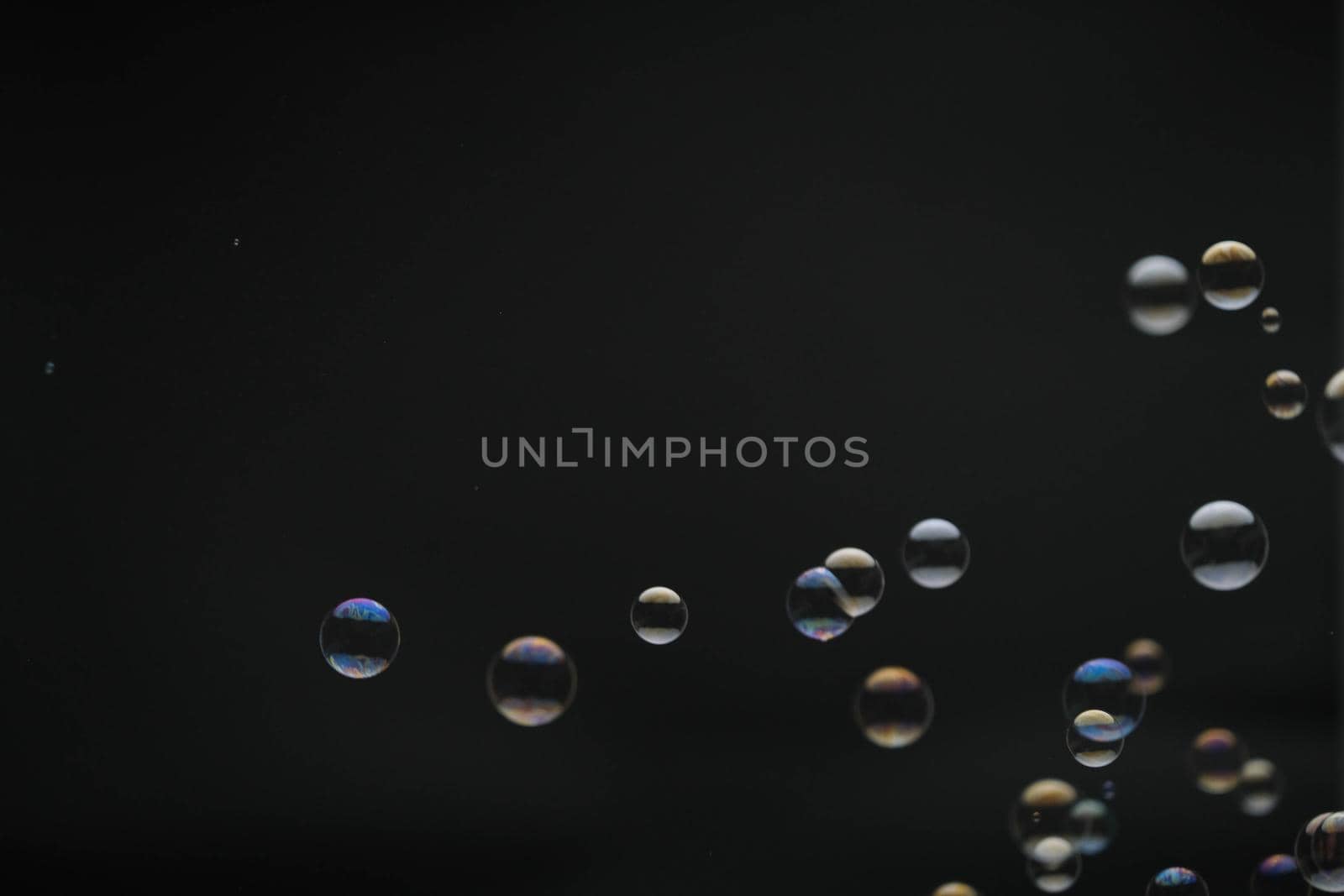 Flying soap bubbles on black background. Abstract soap bubbles with colorful reflections. Soap bubbles in motion background.