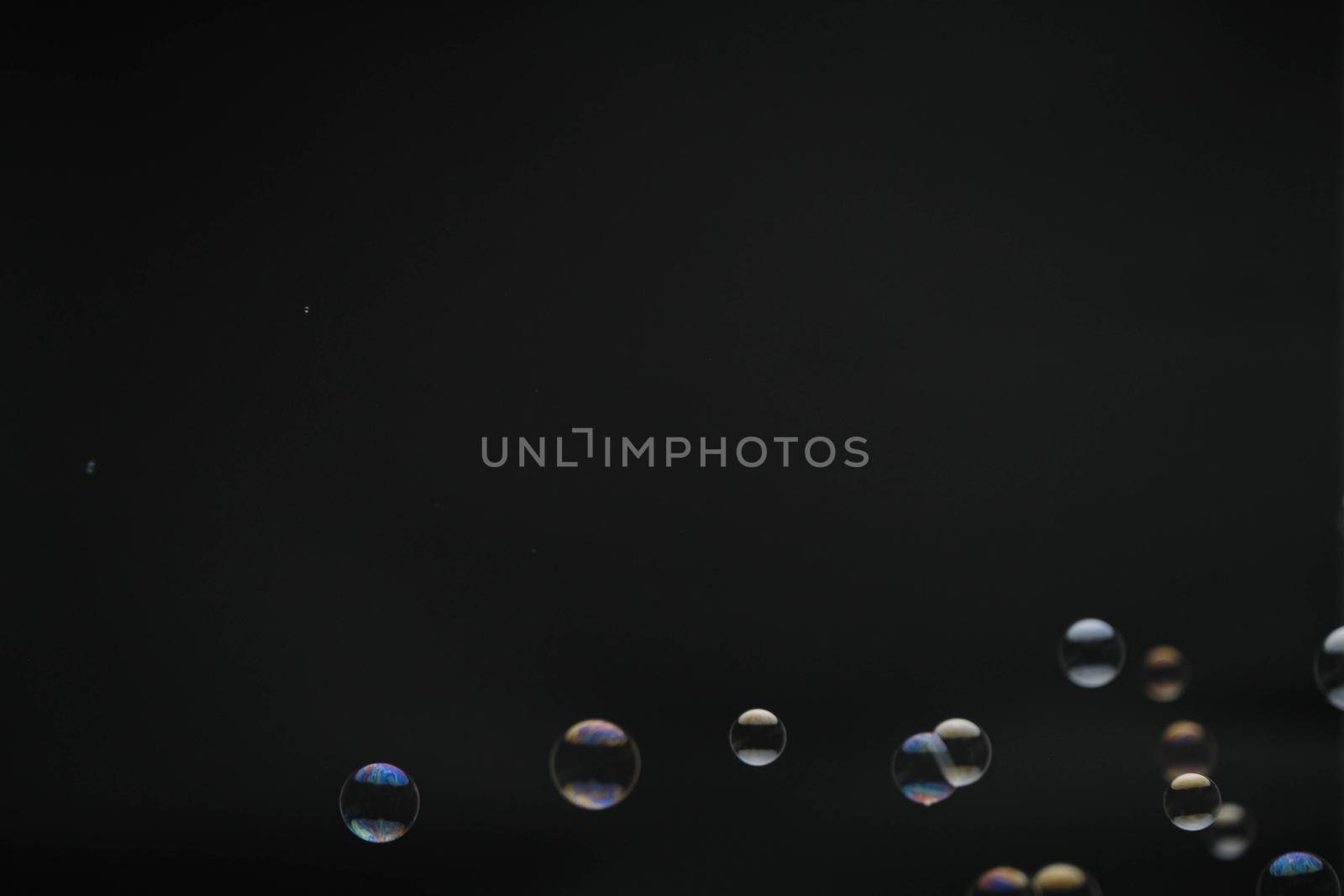Flying soap bubbles on black background. Abstract soap bubbles with colorful reflections. Soap bubbles in motion background.