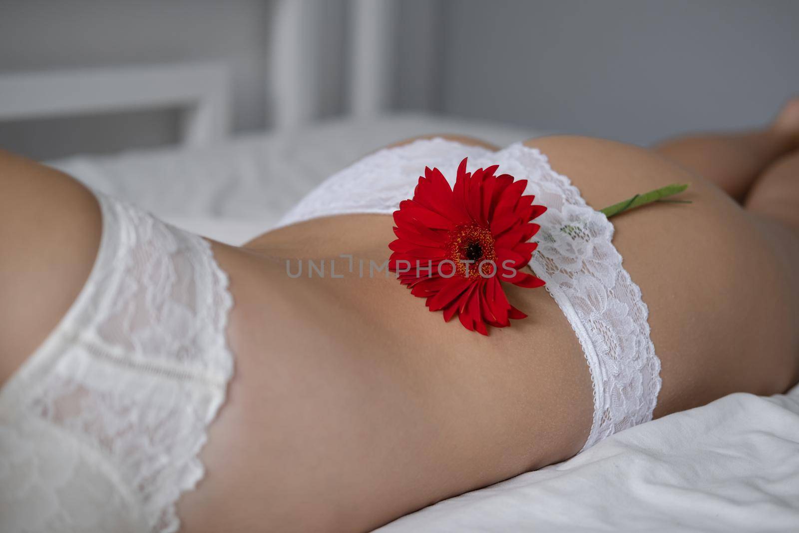 Cropped view of young woman in lace panties with flower near underwear on bed. epilate bikini zone. oncept of female health, reproductive, gynecology. spa body beauty legs.