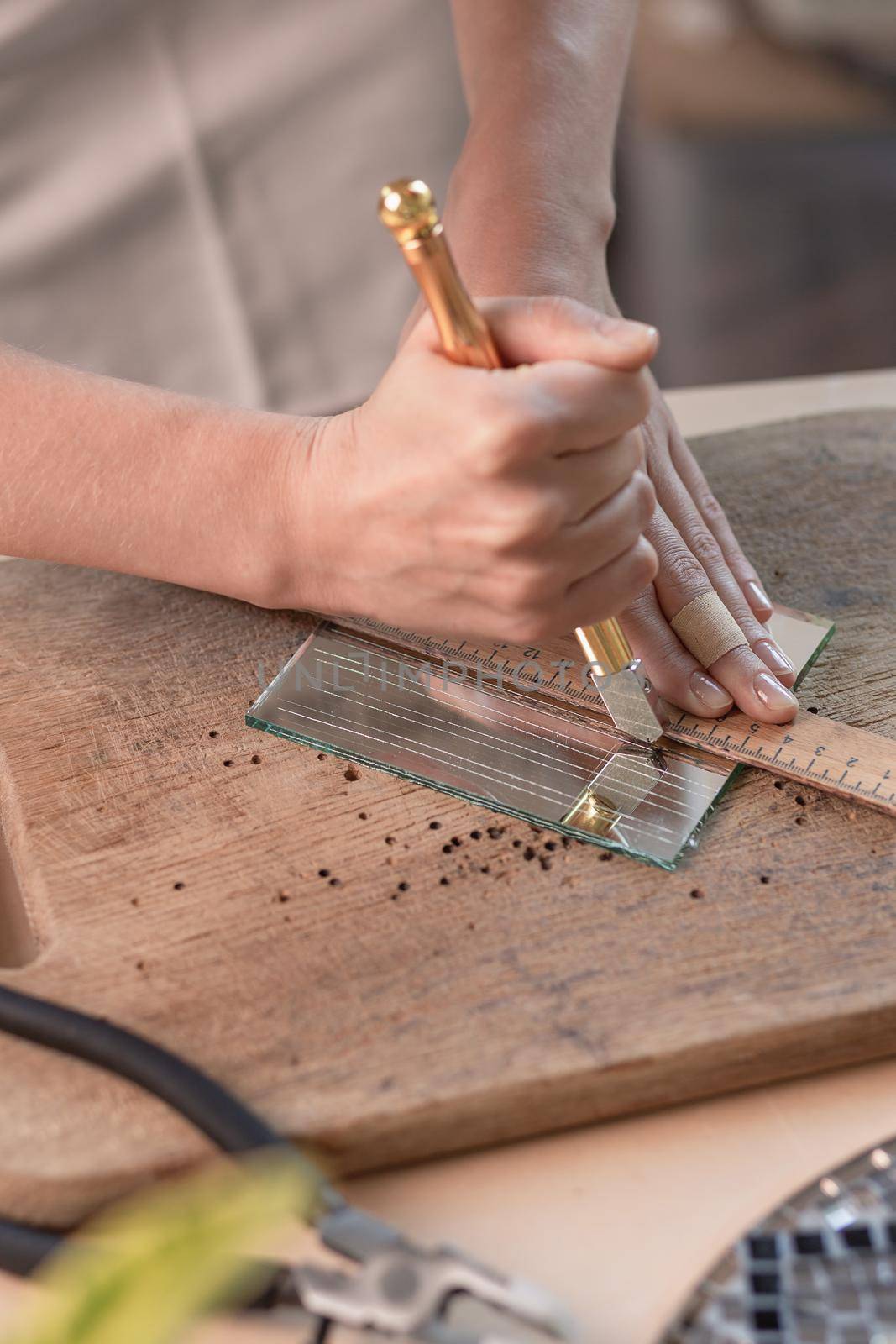 Artist cutting sheets of stained glass into small mosaic squares. Close-up by nazarovsergey