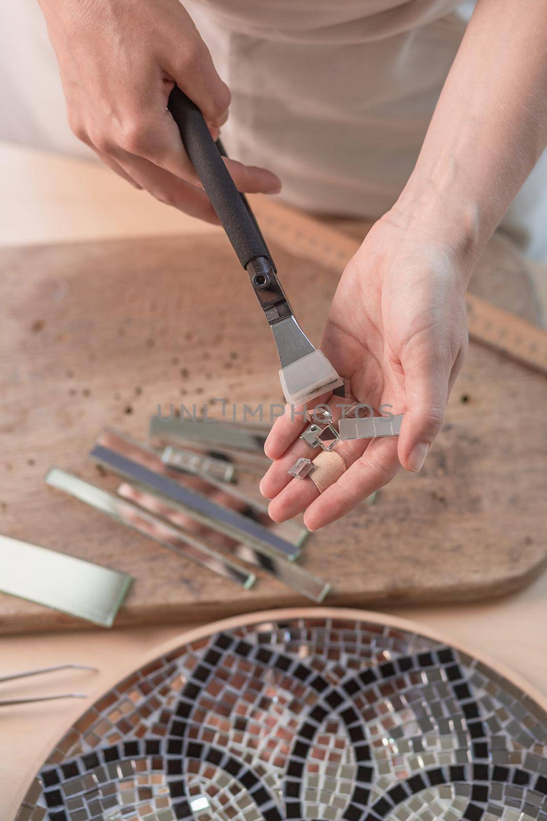 Artist cutting sheets of stained glass into small mosaic squares. Close-up by nazarovsergey