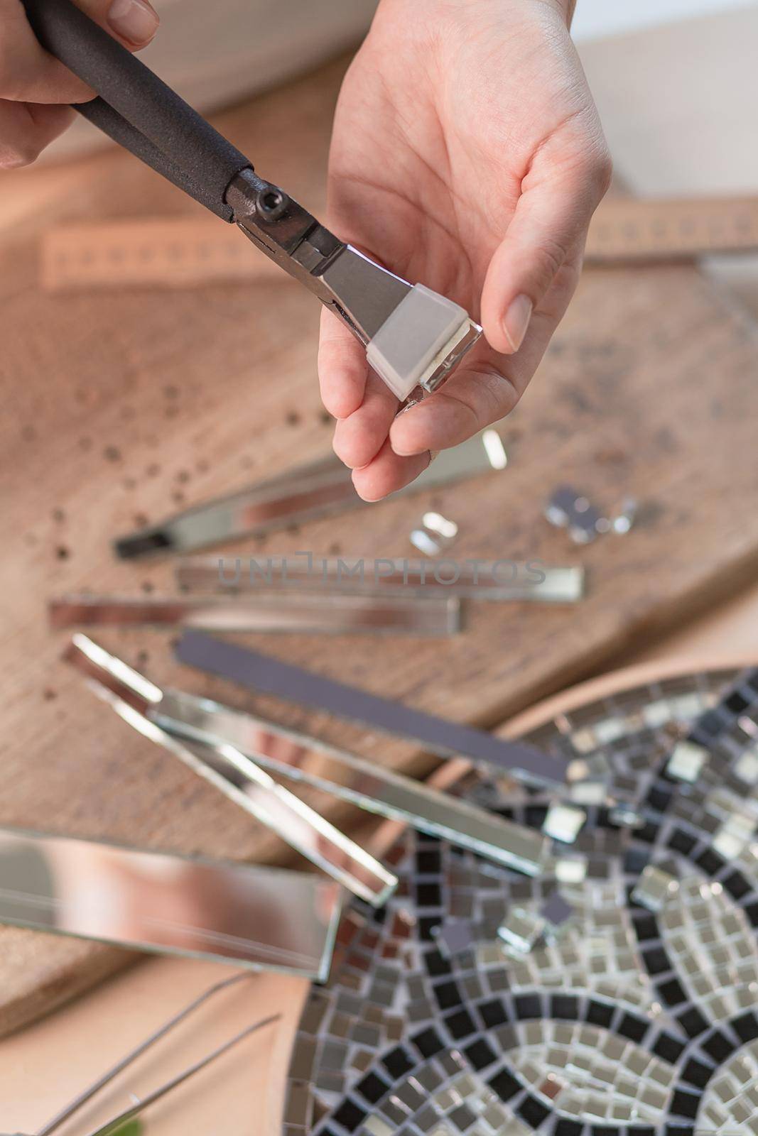 Artist cutting sheets of stained glass into small mosaic squares. Close-up by nazarovsergey