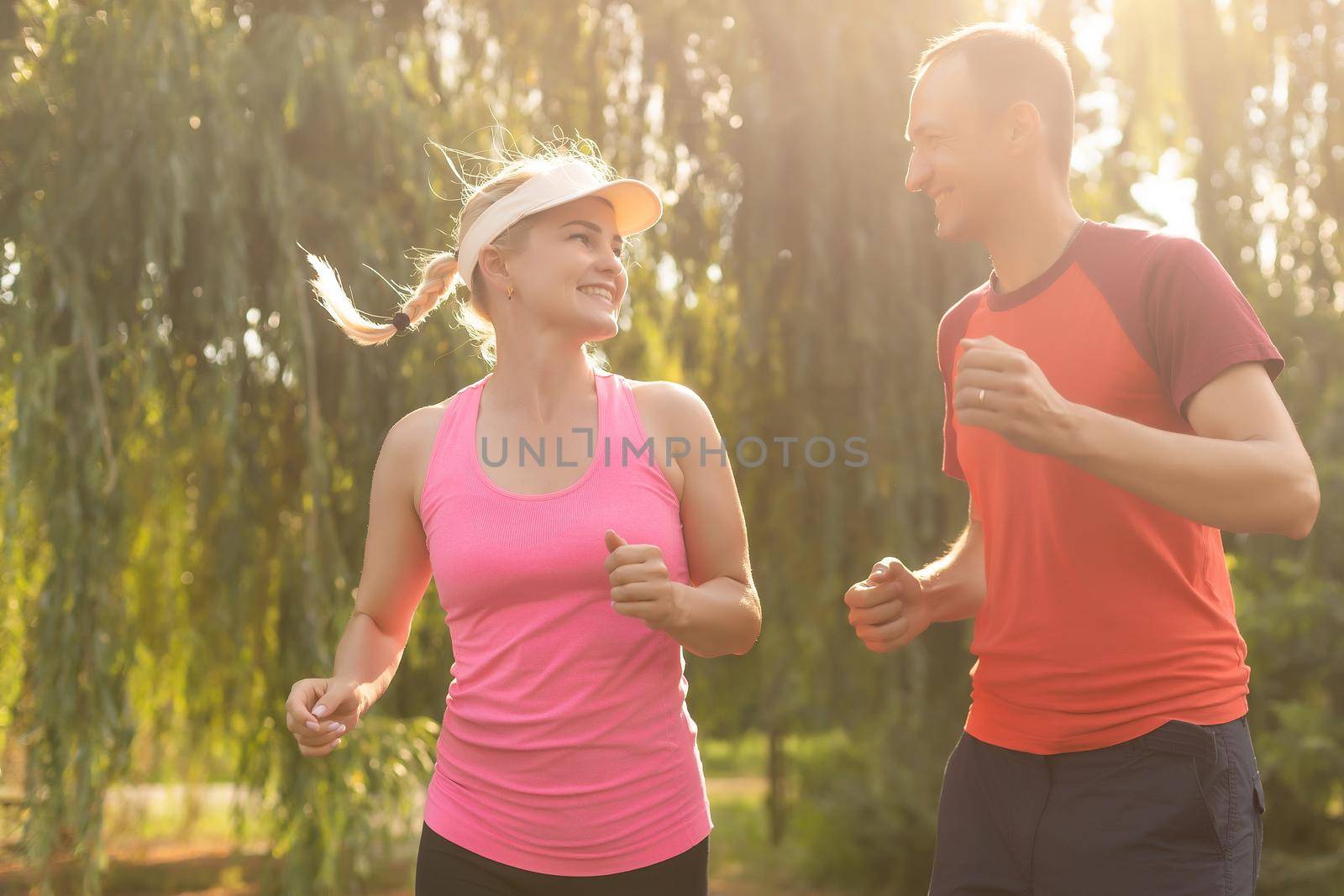 young couple enjoying in a healthy lifestyle while jogging along a country road, exercise and fitness concept by Andelov13
