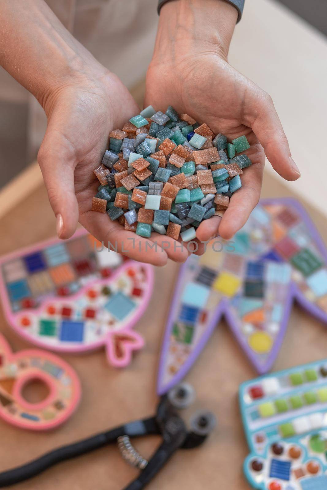 Workplace of the mosaic master: women's hands holding mosaic details in the process of making a mosaic by nazarovsergey