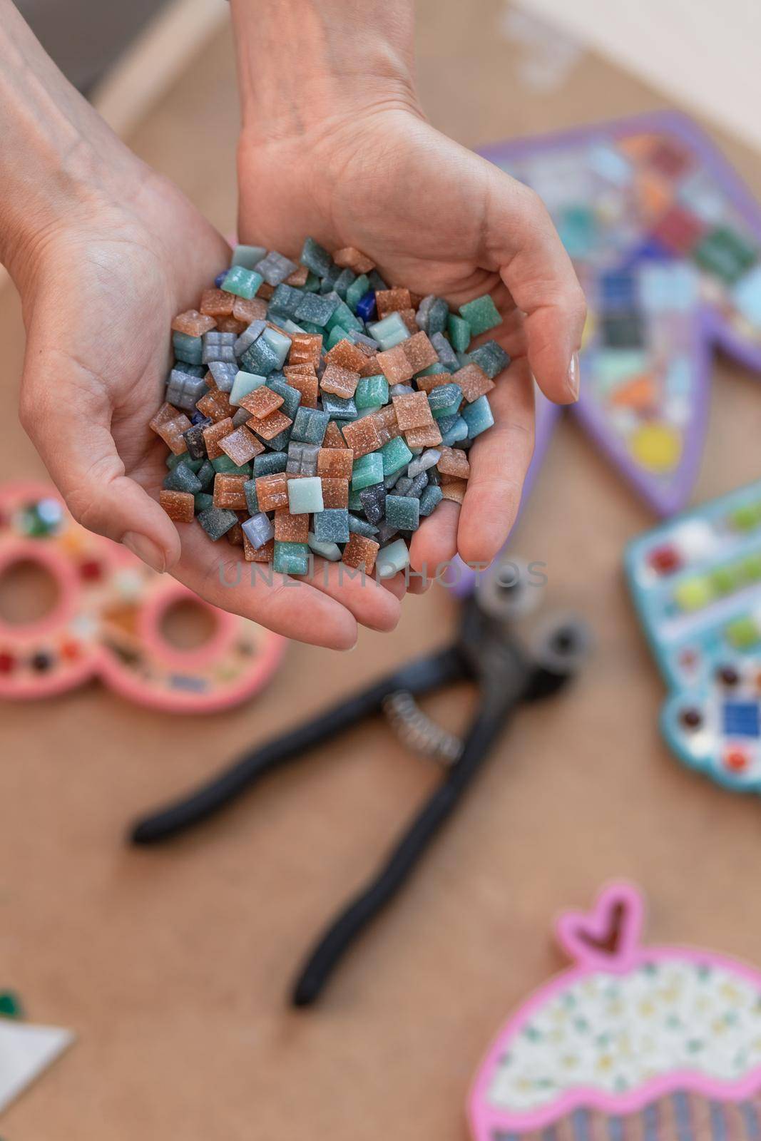 Workplace of the mosaic master: women's hands holding mosaic details in the process of making a mosaic by nazarovsergey