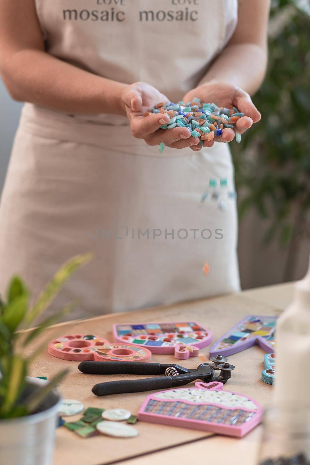 Workplace of the mosaic master: women's hands holding mosaic details in the process of making a mosaic by nazarovsergey