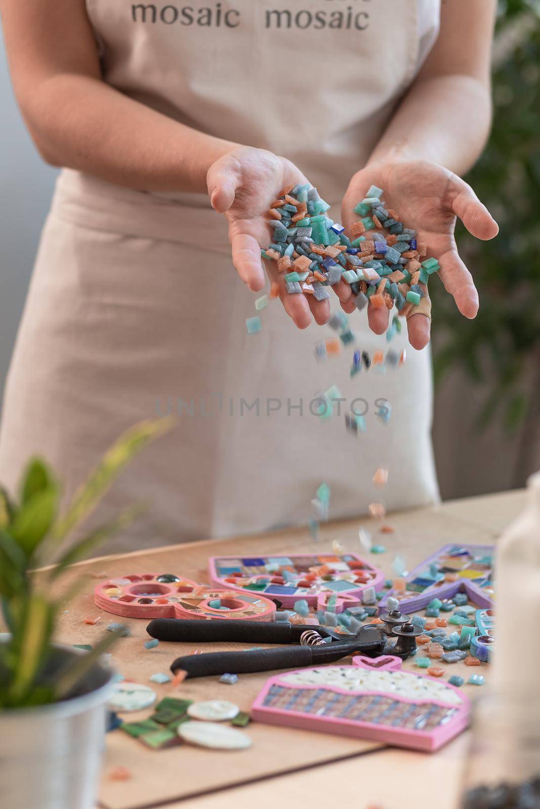 Workplace of the mosaic master: women's hands holding mosaic details in the process of making a mosaic by nazarovsergey