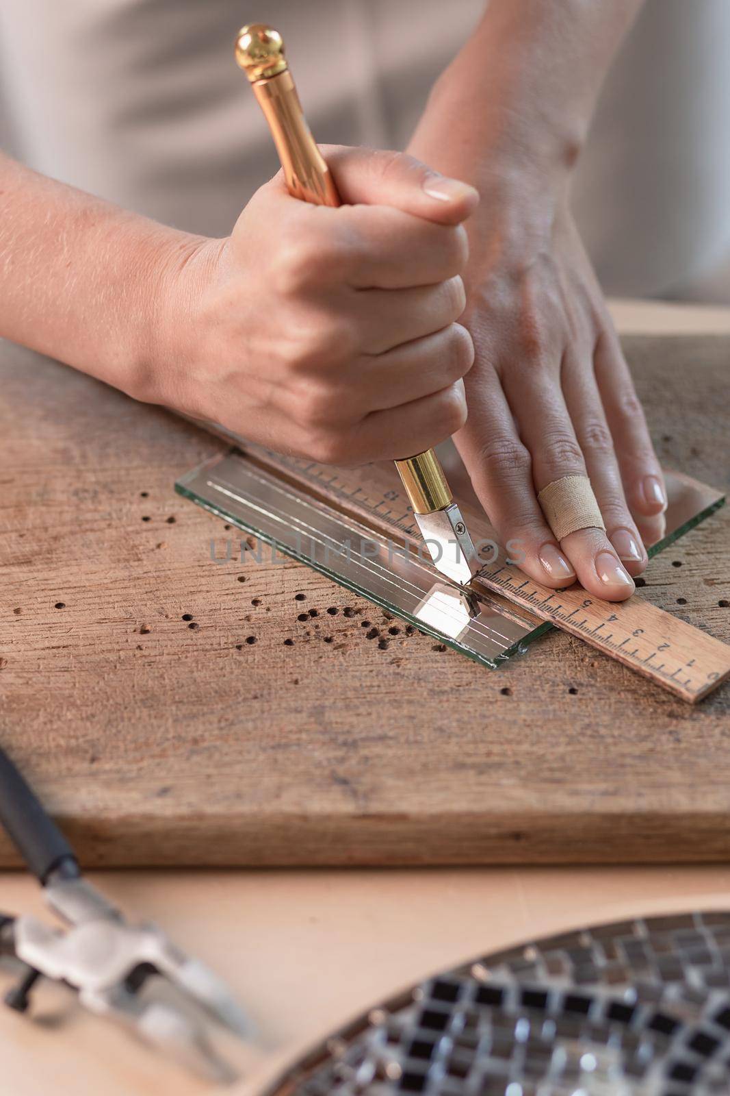 Artist cutting sheets of stained glass into small mosaic squares. Close-up. Workshop. Workplace