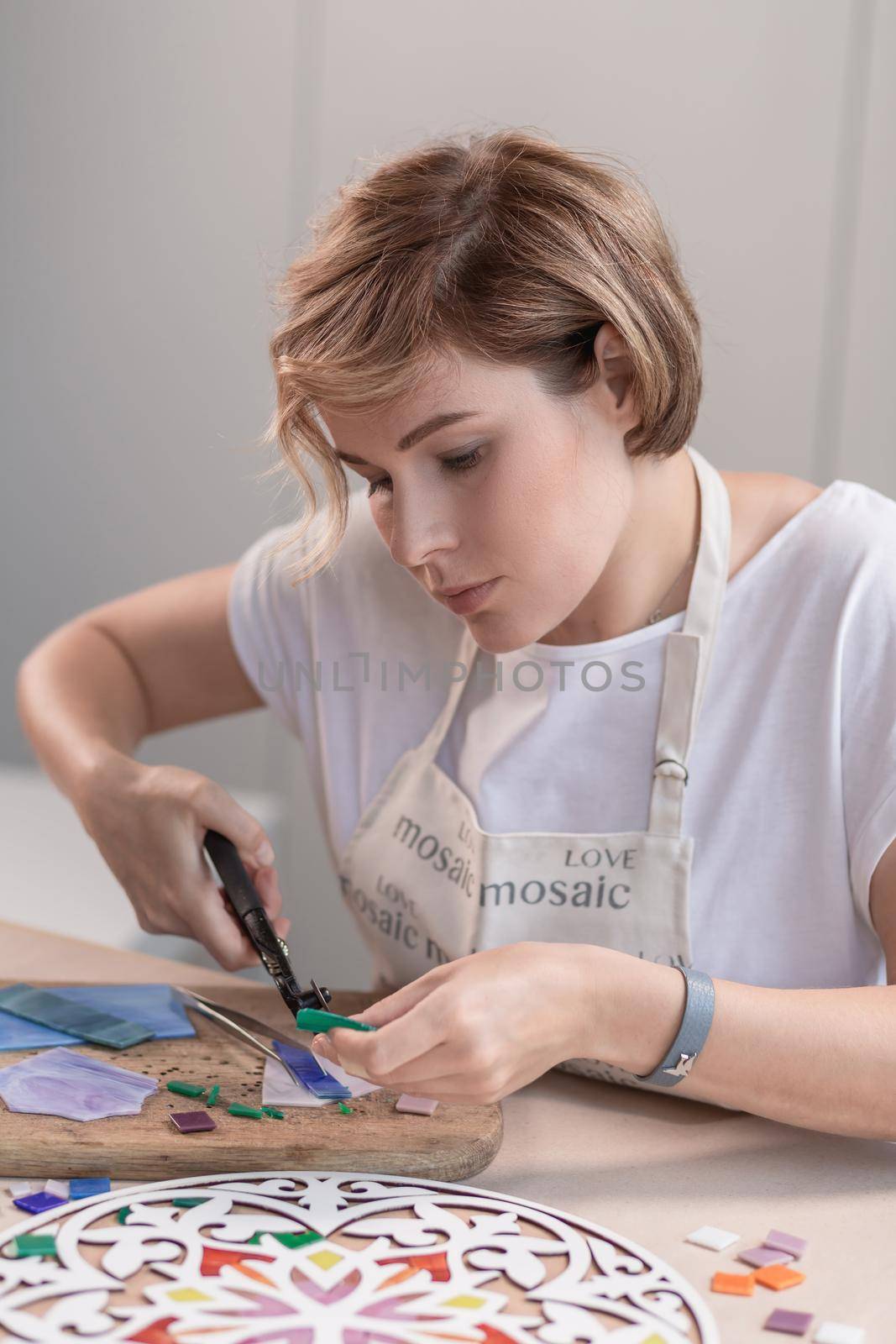 Portrait of master working on new modern colorful mosaic. Close-up. Workshop. Workplace