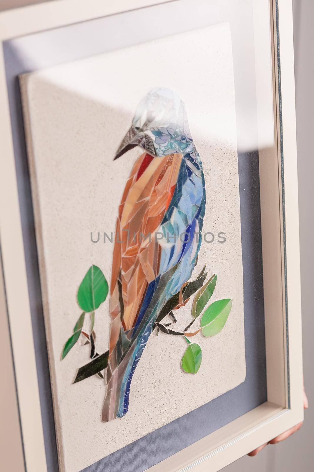 Mosaic bird. Handmade decoration. Frame decoration. The frame stands on the table near the wall