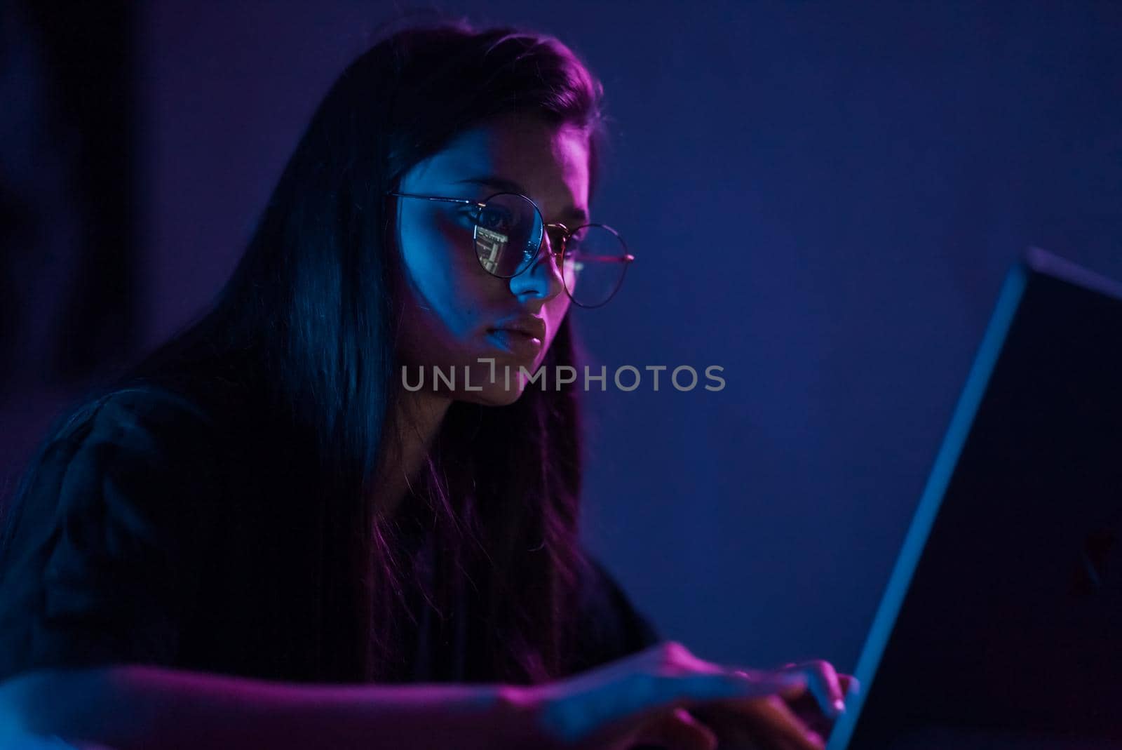 Attractive young woman working in home at night. Girl using laptop.