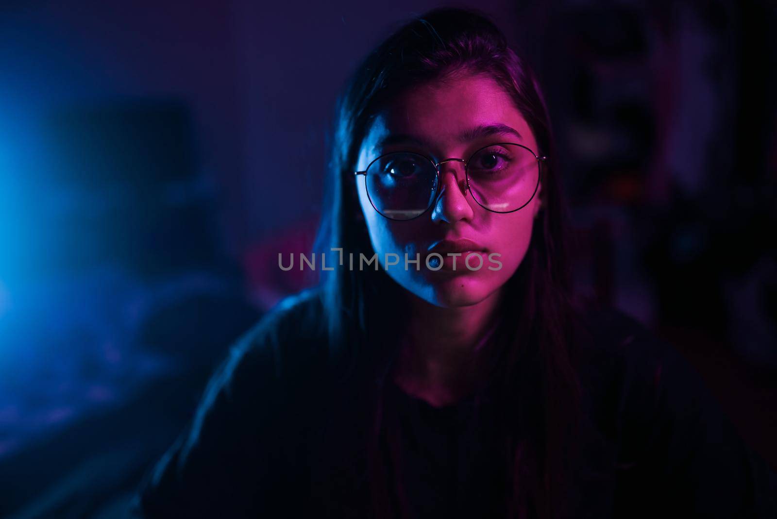 Young brunette woman working at the office at night with serious expression on face. Simple and natural looking at the camera.