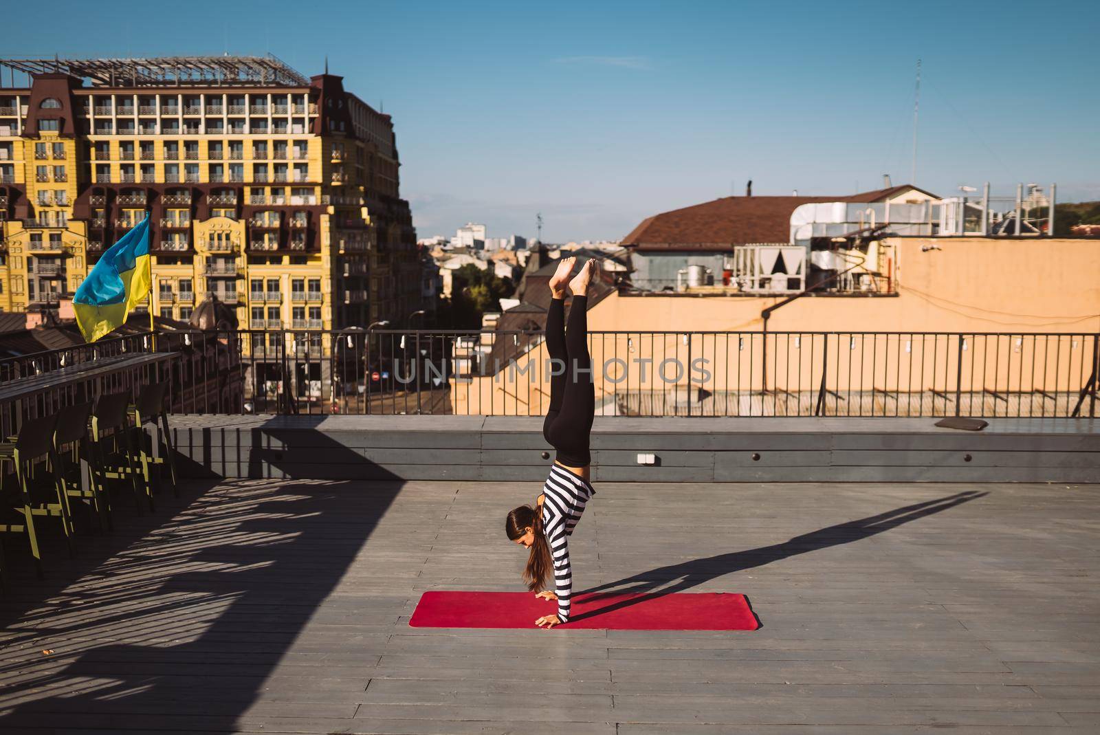 Beautiful young woman working out outdoors and doing yoga handstand exercise on yoga mat