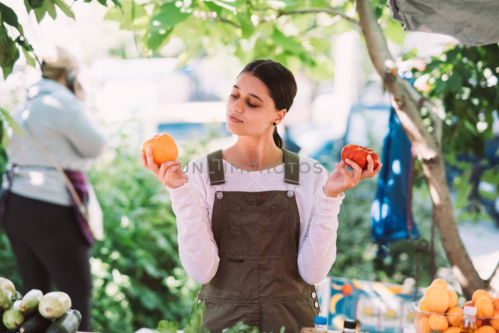 Young positive salesgirl at job, selling sells home-grown vegetables and fruits in vegetable shop