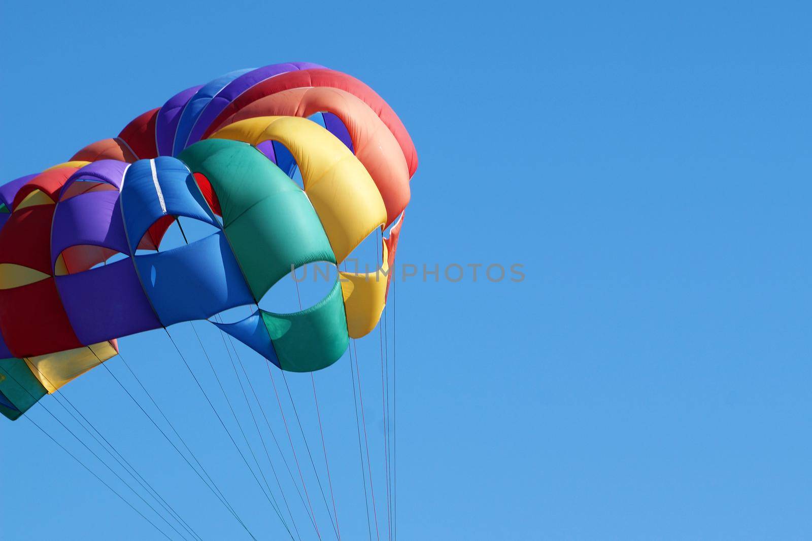 multi-colored parachute against the background of the sunny sky, copy space by Annado