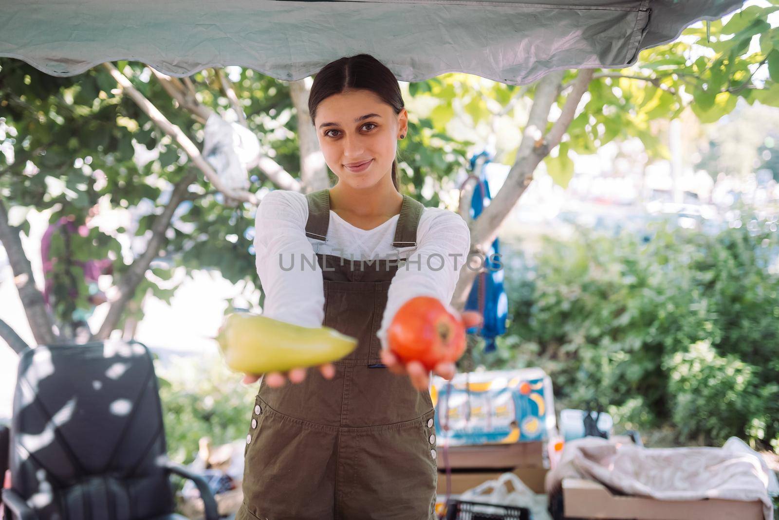 Young positive salesgirl at job, selling sells home-grown vegetables and fruits in vegetable shop