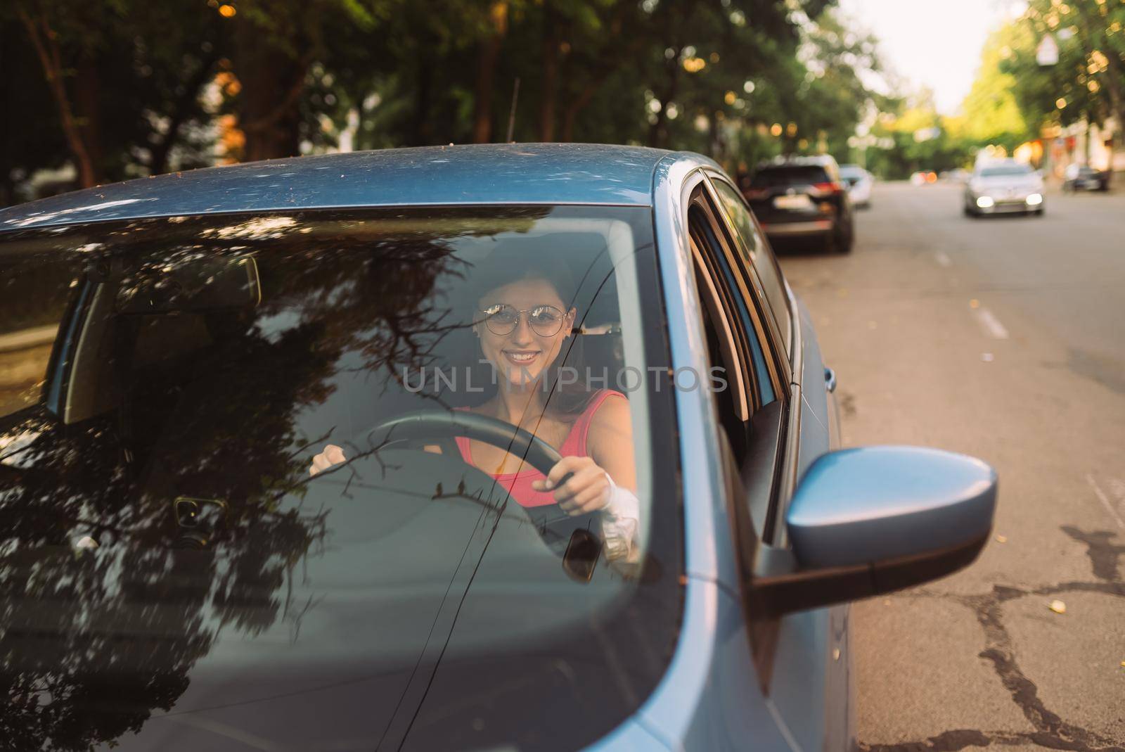 Beautiful Smiling woman driving car, attractive girl sitting in automobile, outdoors summer portrait.