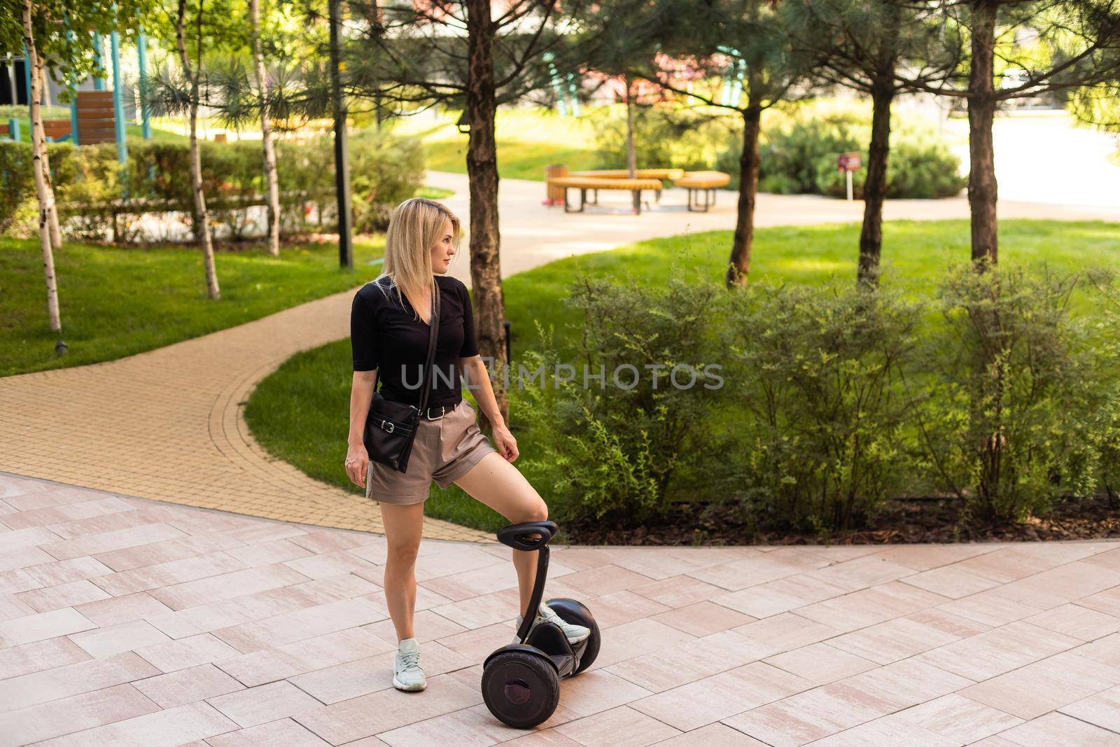 woman riding electric mini segway hover board scooter in green park. Good summer weather, ecological urban transportation technology and pretty model.Electric self-balancing scooter board.