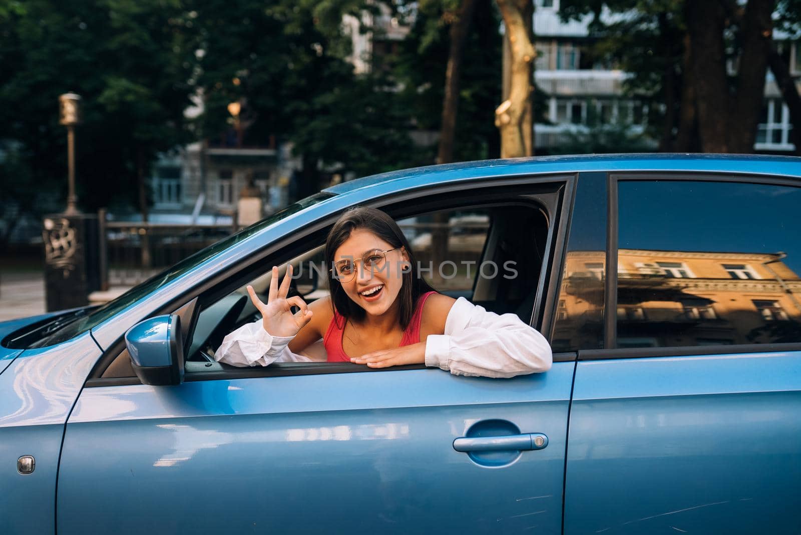Happy woman portrait in a car in the city, looking out of the window. Travel and vacations concepts