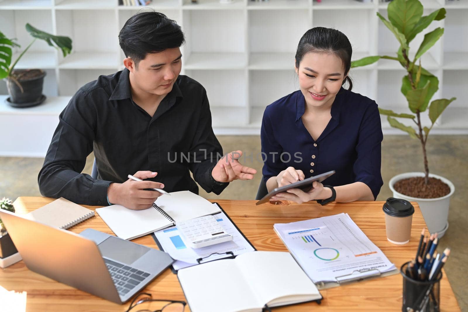 Two business colleagues analyzing financial information together in office. by prathanchorruangsak