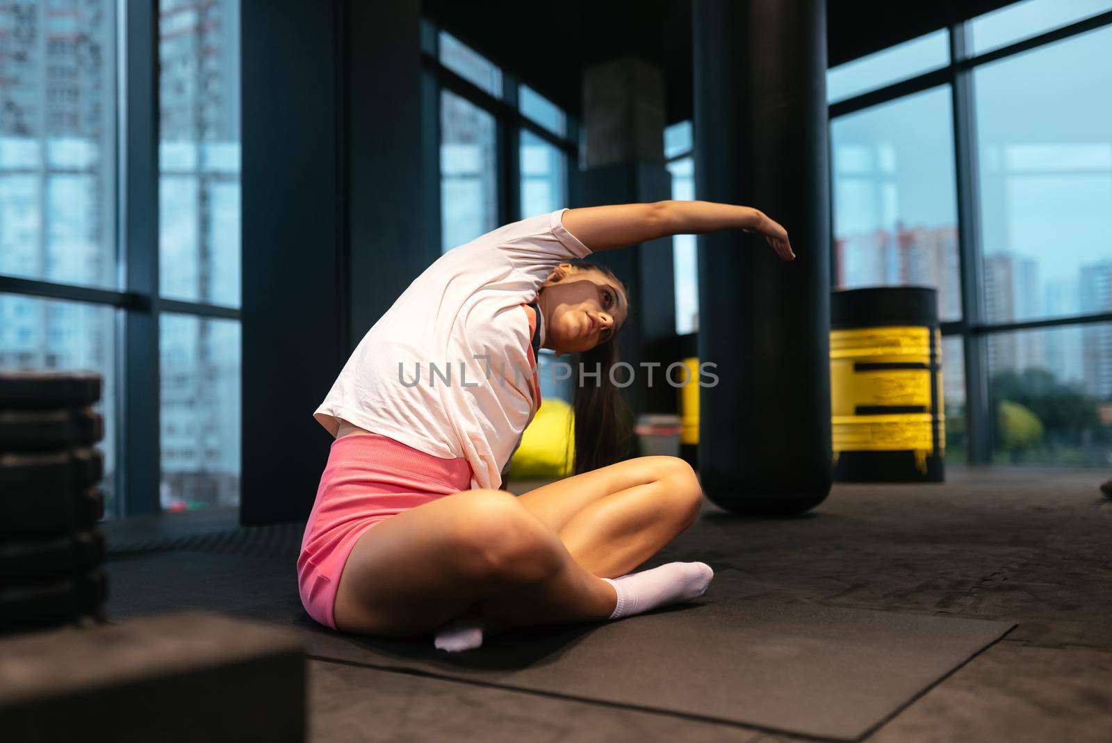 Young sporty woman practicing yoga, working out, wearing sportswear, indoor full length, yoga studio