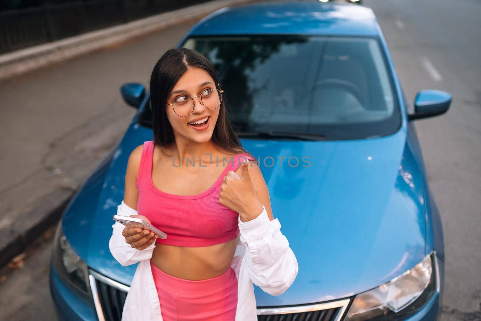 Woman using mobile phone near car