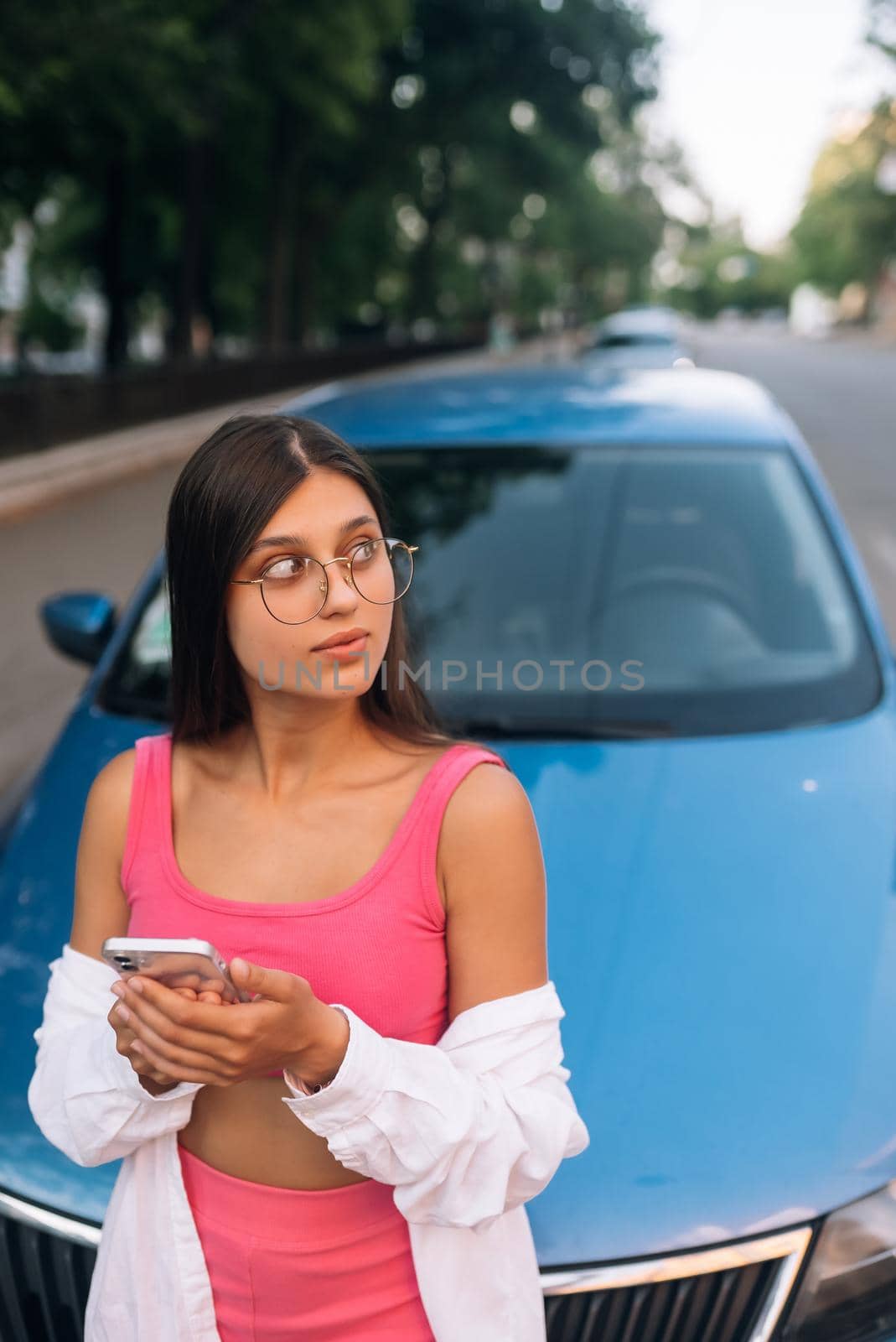 Woman using mobile phone near car at the street by teksomolika