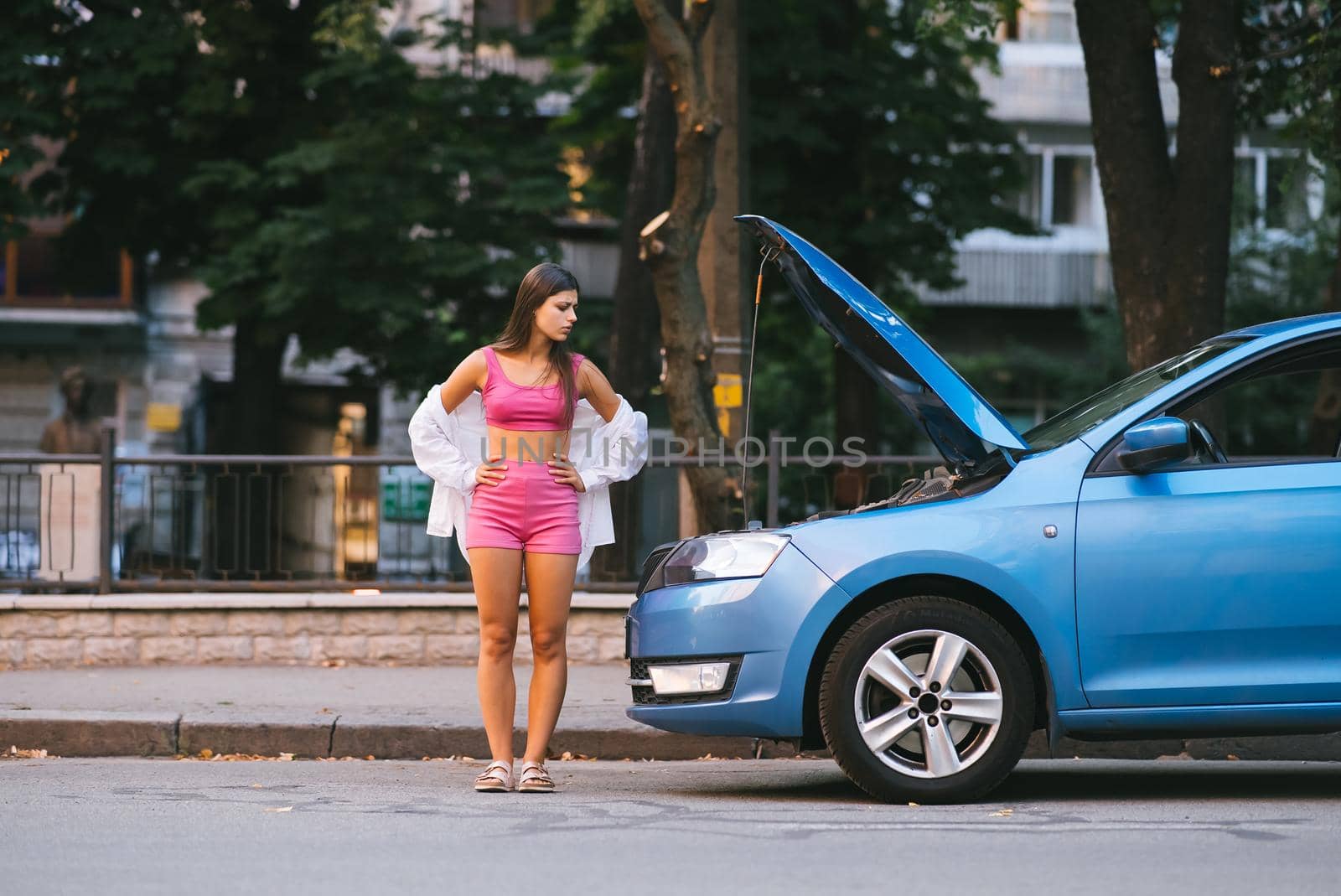 Woman with broken down car on the road she feeling serious and stressed. Look for someone help.