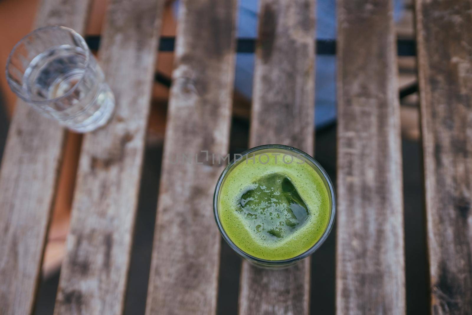 Iced green matcha latte tea in a glass on wooden table at modern style cafe. Tasty morning drinks.