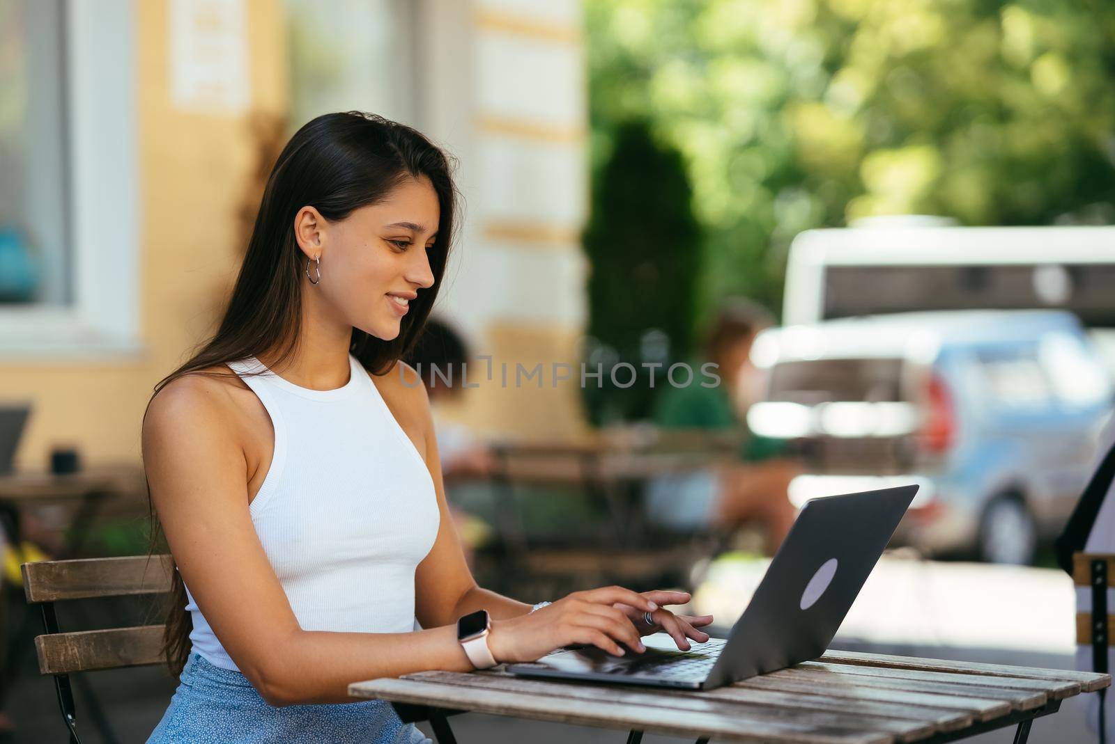 Woman working on laptop at outdoors cafe