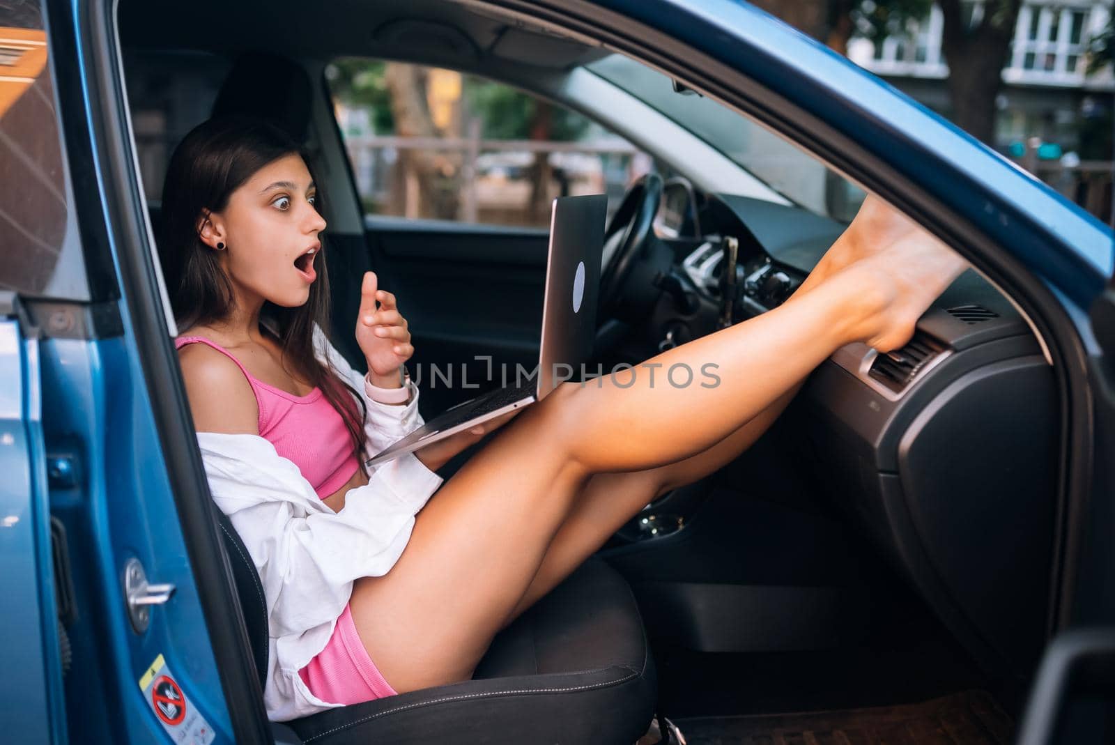 Young woman using laptop in her car. Close view