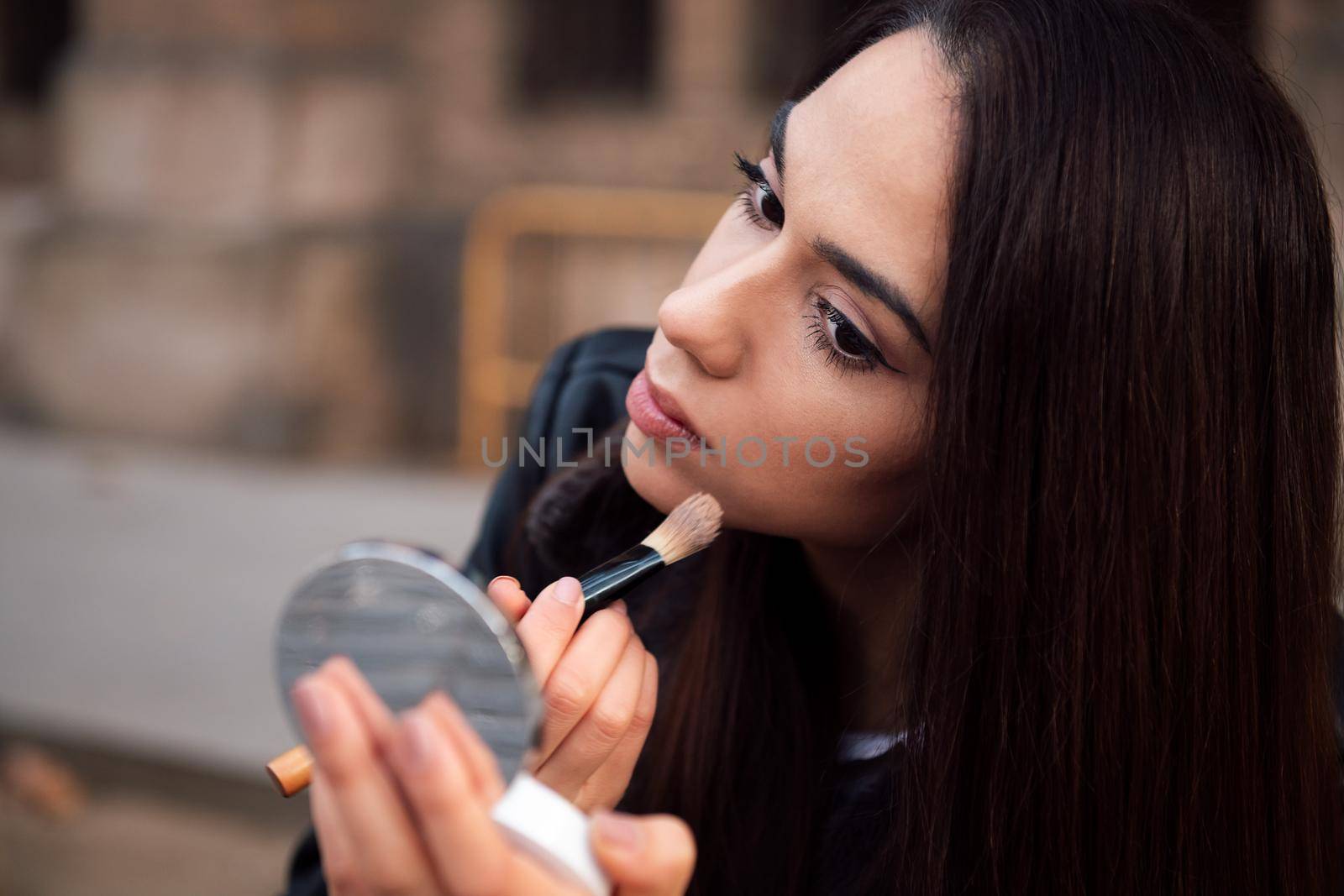 young woman touching up her makeup in the street by raulmelldo