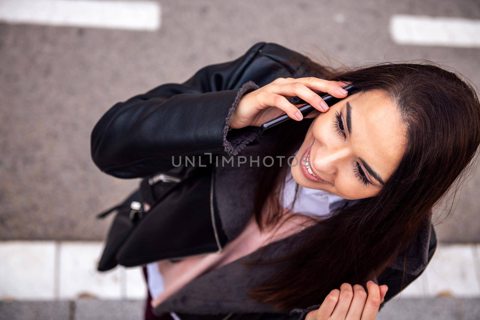top view of a smiling woman calling on the phone in the street, concept of technology and urban lifestyle, copyspace for text