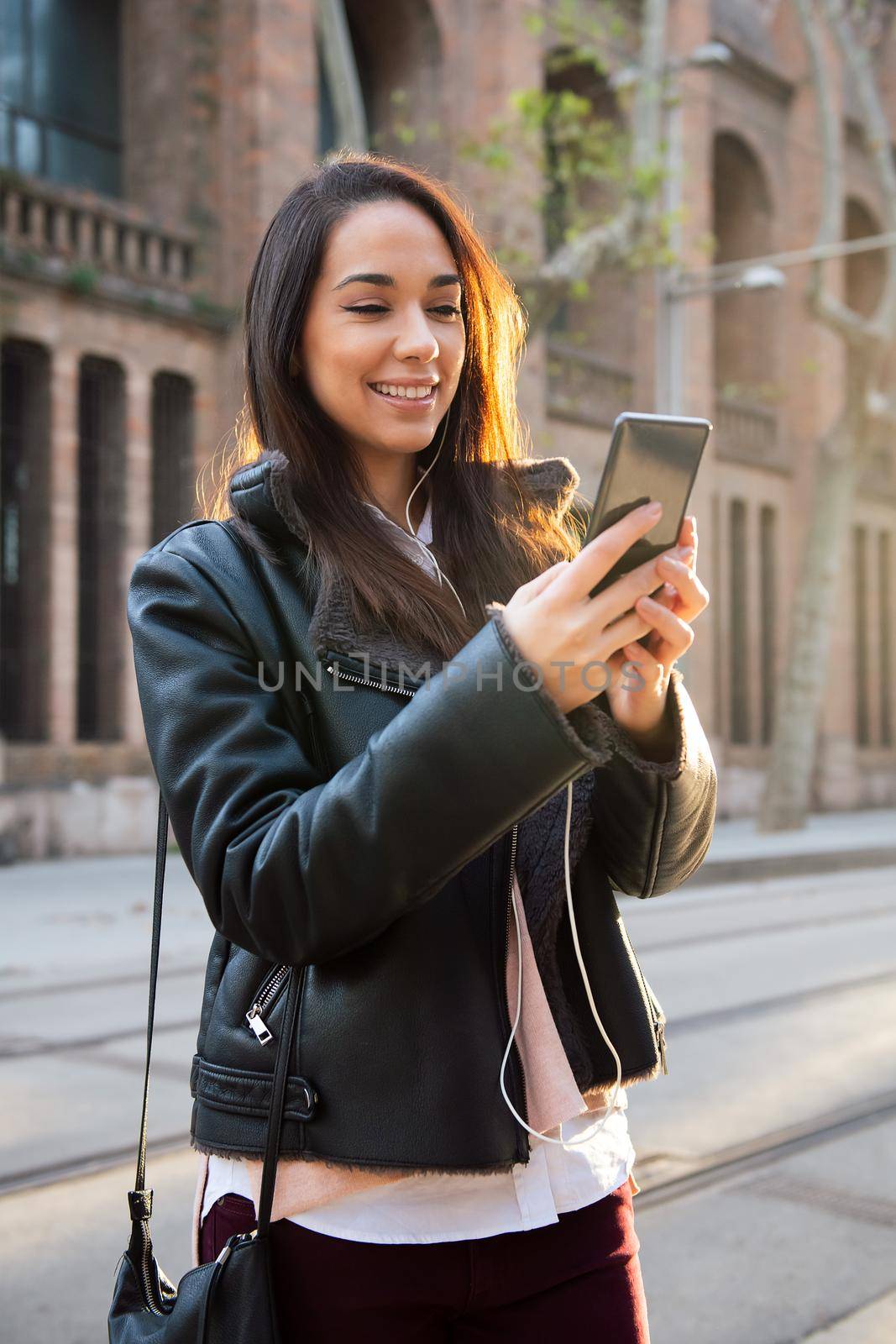 smiling young woman reading a message at her phone by raulmelldo