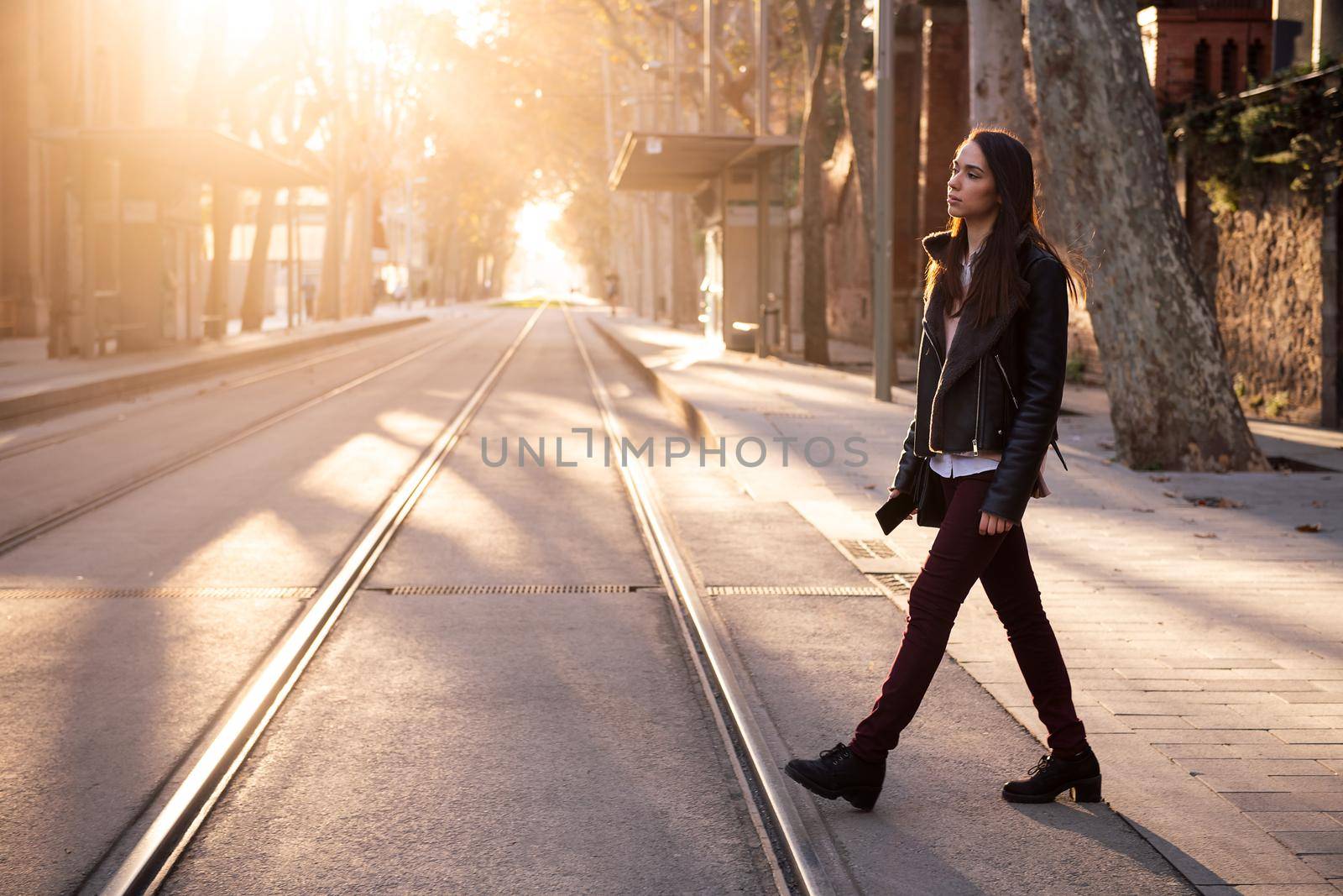 stylish young woman crossing the street at sunset, concept of urban lifestyle, copyspace for text