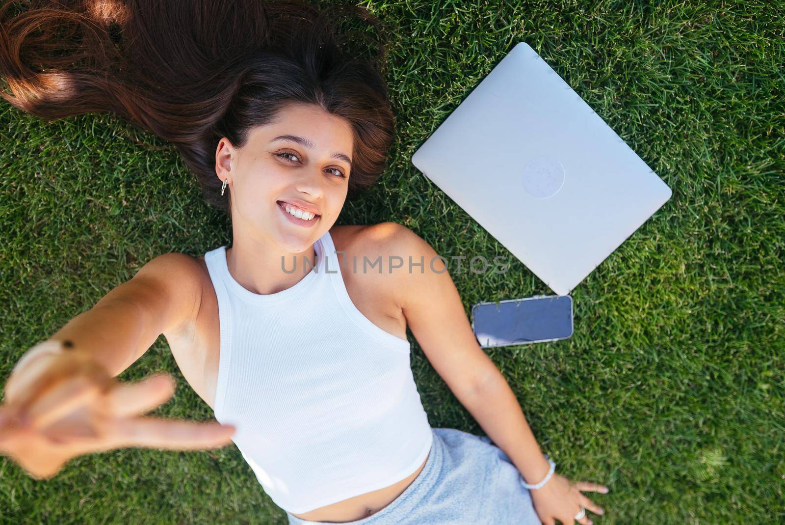 Young fit attractive woman lying on green lawn park. Perks of freelance concept. Background, copy space