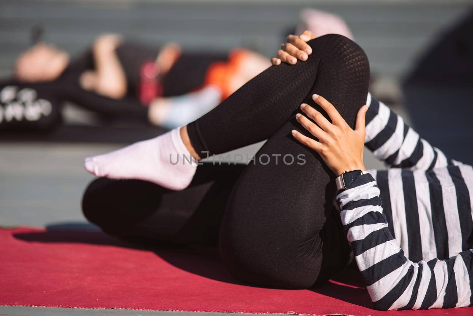 Yogi woman and diverse group of young sporty people practicing yoga, female students training at house's roof. Well being, wellness concept